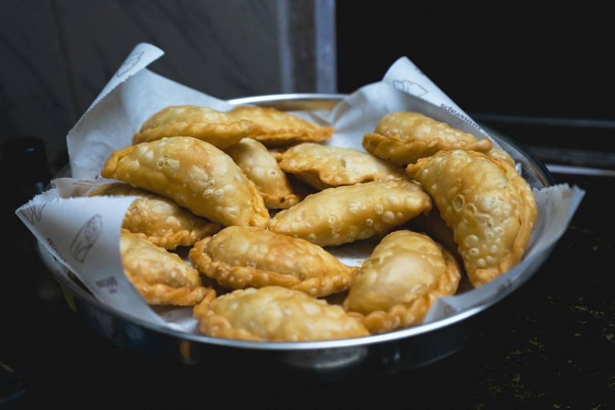 Sejumlah panada goreng berwarna cokelat keemasan tersaji di atas piring sebagai ilustrasi makanan khas.