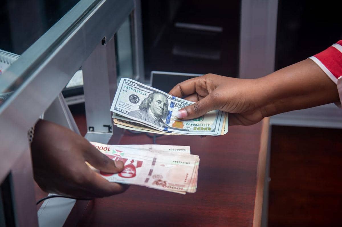ilustrasi dua orang yang saling bertukar mata uang AS dan mata uang lokal di konter bank