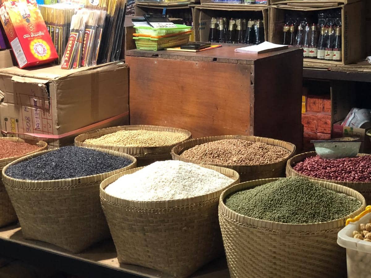 Aktivitas warga dan pedagang di pasar tradisional Tabanan, Bali, dengan deretan kios serta barang dagangan.
