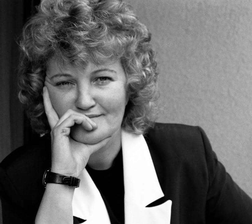 Potret Brenda Fricker dengan rambut putih pendek, mengenakan busana gelap dan tersenyum ke arah kamera.