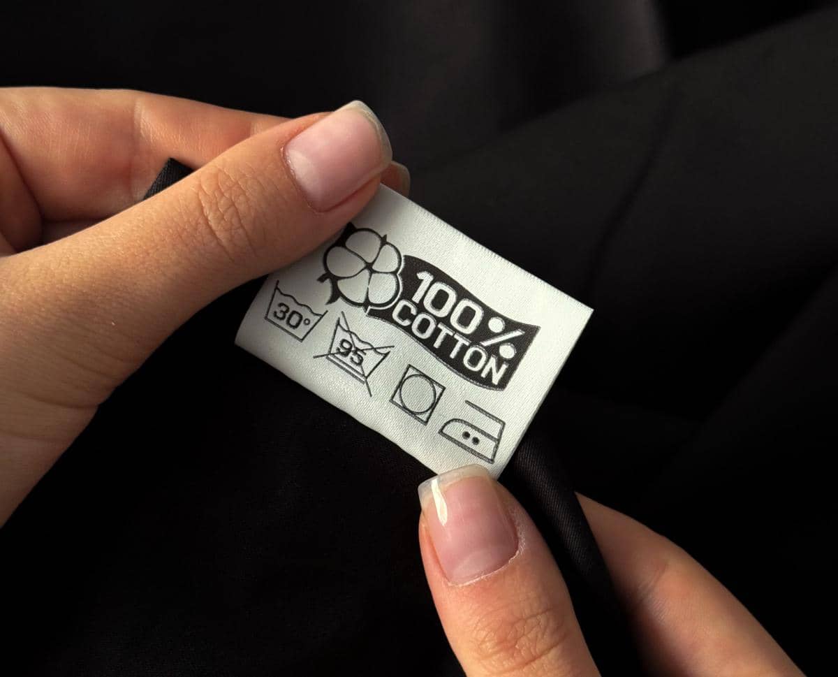 Seseorang memeriksa simbol perawatan pada label pakaian untuk mengetahui cara mencuci, mengeringkan, dan menyetrika dengan benar.