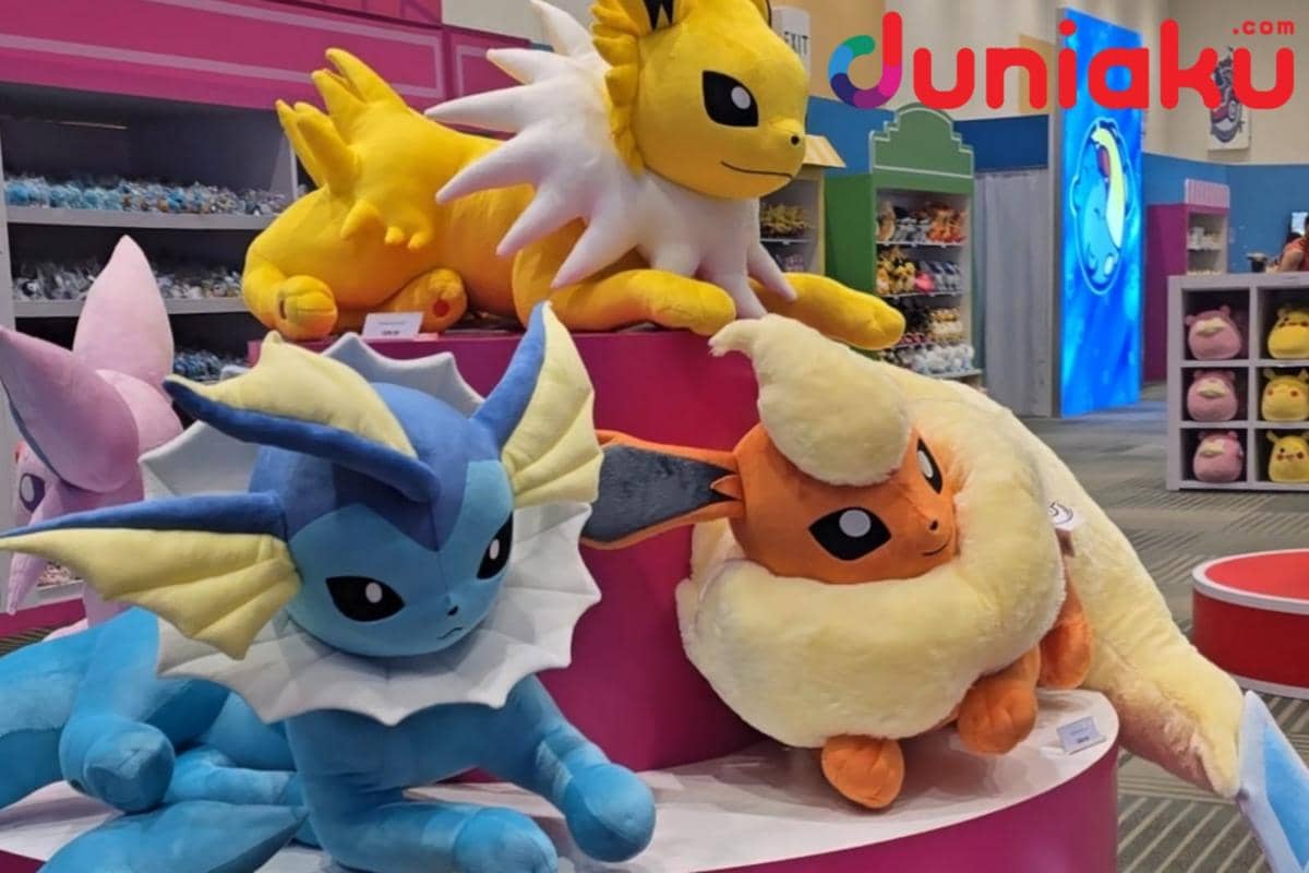 Deretan plush besar berbagai evolusi Eevee dipajang di area Pokémon Center dengan warna dan ekspresi yang beragam.