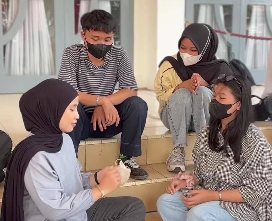 Seorang mahasiswa Unsri mengenakan masker putih dan membawa tas saat beraktivitas di lingkungan kampus.