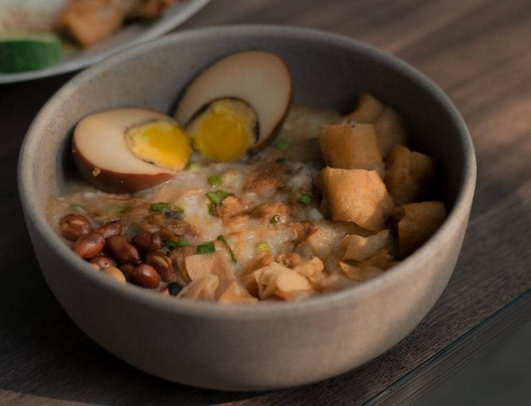 Ilustrasi sajian bubur ayam, makanan khas Indonesia berbahan bubur nasi yang disajikan sebagai hidangan hangat.