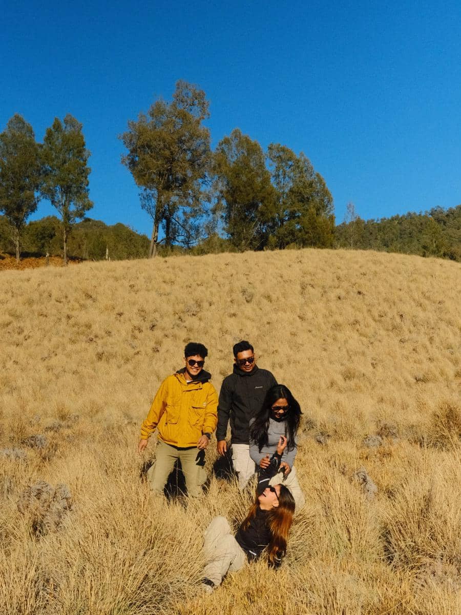 Bella Graceva berjalan di jalur Cemoro Kandang saat pendakian Gunung Semeru, dikelilingi lanskap pegunungan.