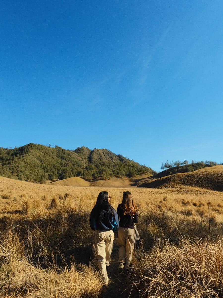 Bella Graceva berjalan di jalur Cemoro Kandang saat pendakian Gunung Semeru, dikelilingi lanskap pegunungan.