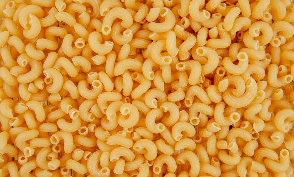 Ilustrasi makaroni berbentuk pipa pendek berwarna kuning keemasan sebagai sajian makanan berbahan pasta.