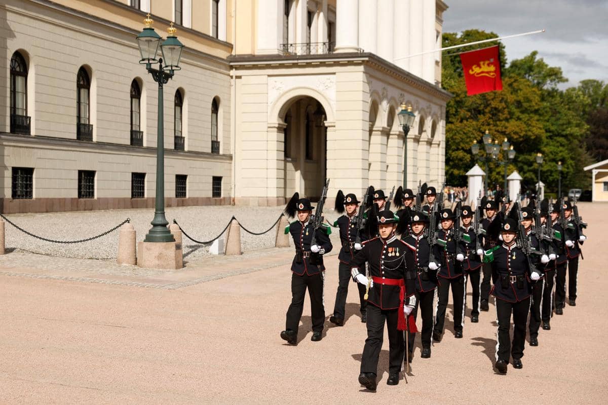 Anggota Pasukan Pengawal Kerajaan Norwegia berbaris di luar Istana Kerajaan saat bendera kerajaan dikibarkan setengah tiang di istana terseb