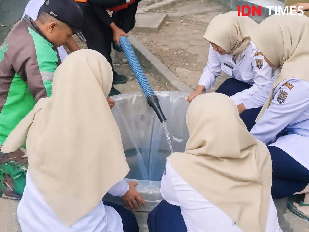 Petugas BPBD mengisi sumur kering di SD Kubangkangkung dengan air dalam plastik agar tidak meresap ke tanah.