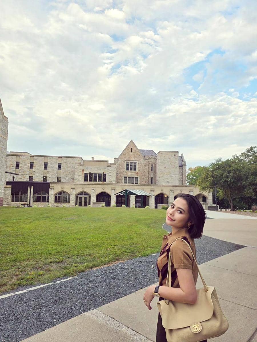 Prilly Latuconsina berpose di area Kampus Omara Esteghlal di Amerika Serikat, mengenakan busana kasual dan tersenyum ke kamera.