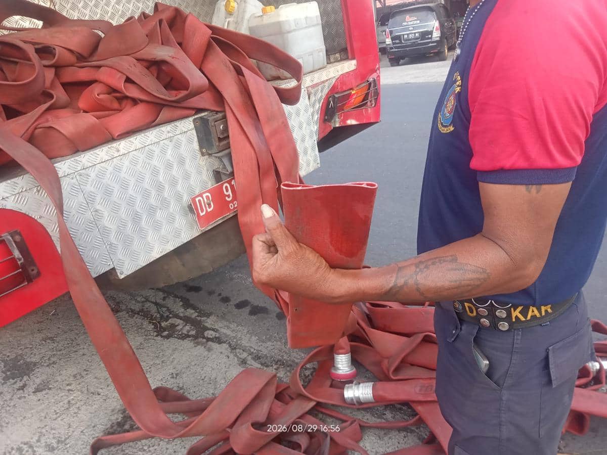 Petugas Damkar Bitung memperlihatkan selang pemadam yang dipotong orang tak dikenal saat kebakaran lahan.