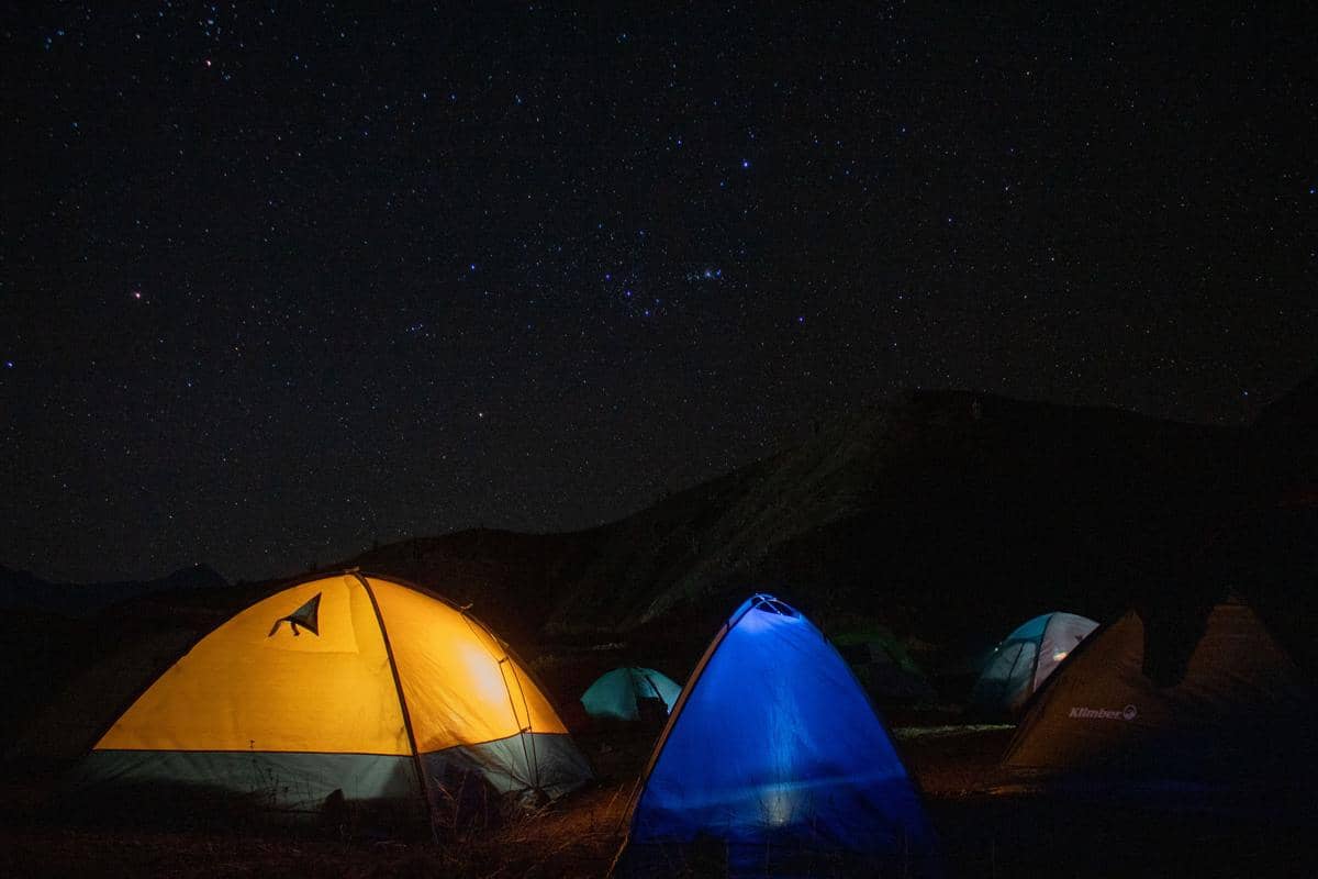ilustrasi beberapa tenda di area camp saat malam hari