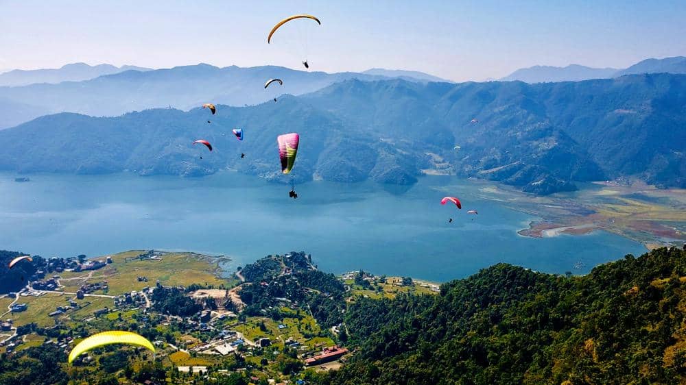 ilustrasi wisatawan melakukan paragliding di tepian Danau Phewa