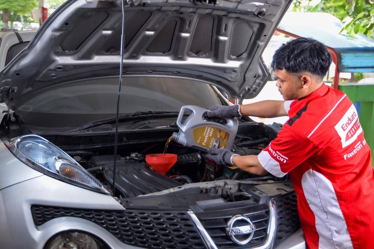 Mekanik Enduro Service mengganti oli Pertamina Fastron pada mesin mobil konsumen di SPBU Pertamina.