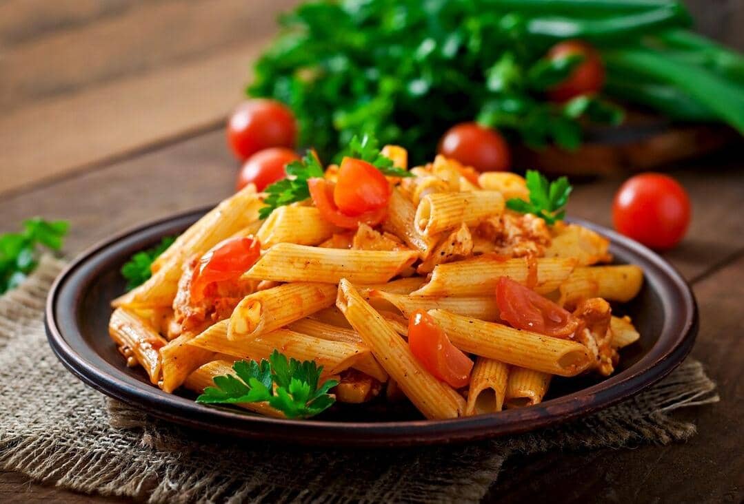 Ilustrasi pasta penne dengan potongan tabung pendek bertekstur, disajikan sebagai visual makanan sederhana.