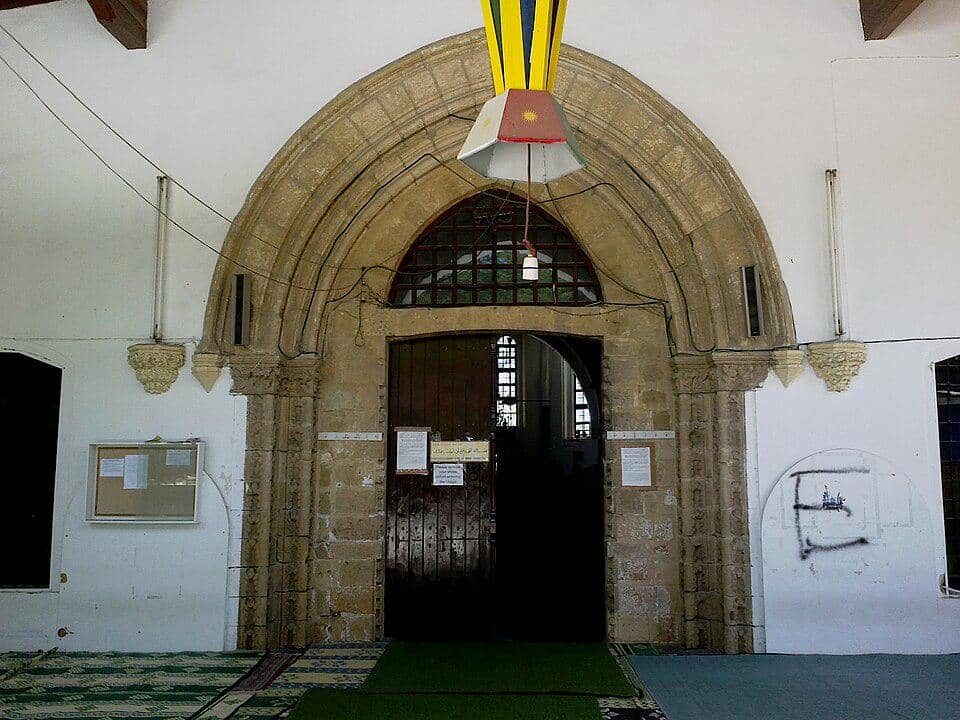 Pintu masuk Masjid Omeriye di Nicosia, Siprus, dengan lengkungan batu dan fasad bangunan bersejarah yang kokoh.