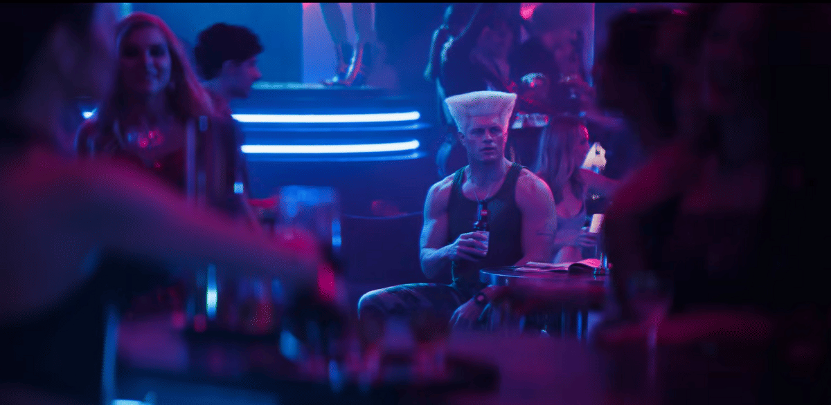 Guile duduk sambil minum di klub malam yang remang-remang dalam adegan film Street Fighter produksi Paramount Pictures.