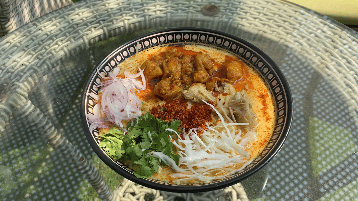 Ilustrasi semangkuk ohn no khao swe, mi kuah kari santan khas Myanmar dengan telur rebus serta aneka pelengkap.