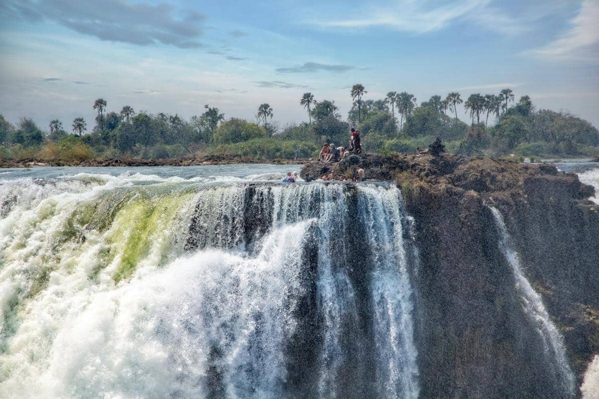 Wisatawan berenang di Devil's Pool yang terkenal di tepi Air Terjun Victoria.