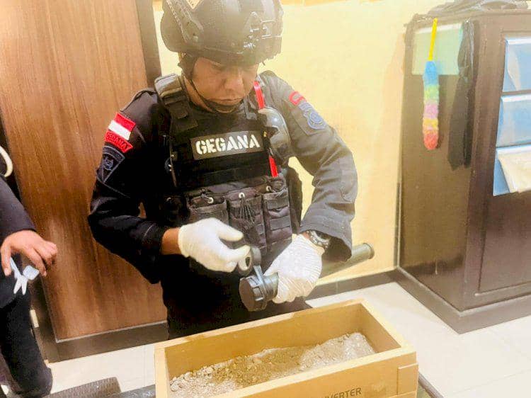 Personel Tim Jibom Gegana memeriksa peluru dan granat yang diserahkan petani kepada Polres Malaka di atas meja.