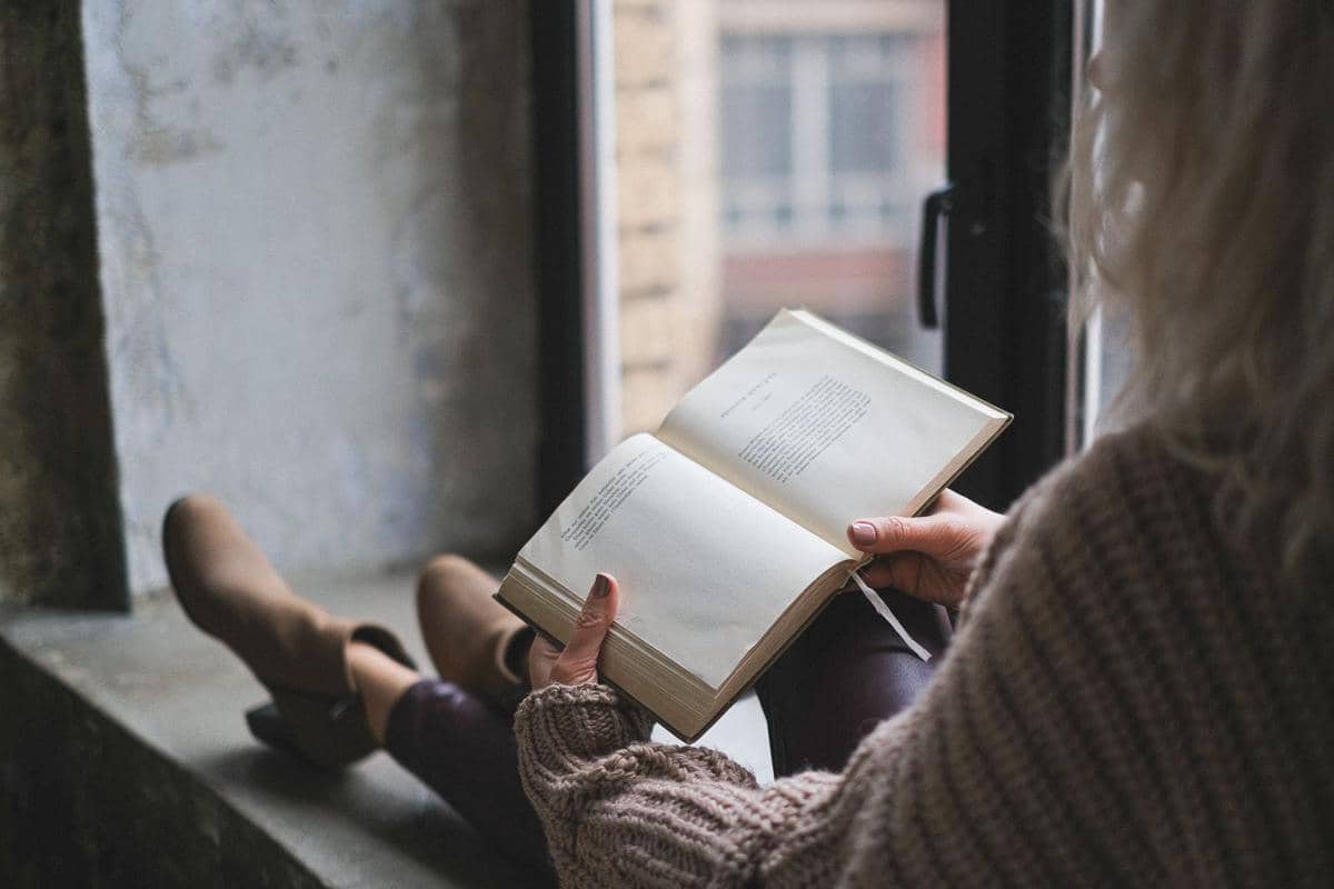 membaca buku di dekat jendela