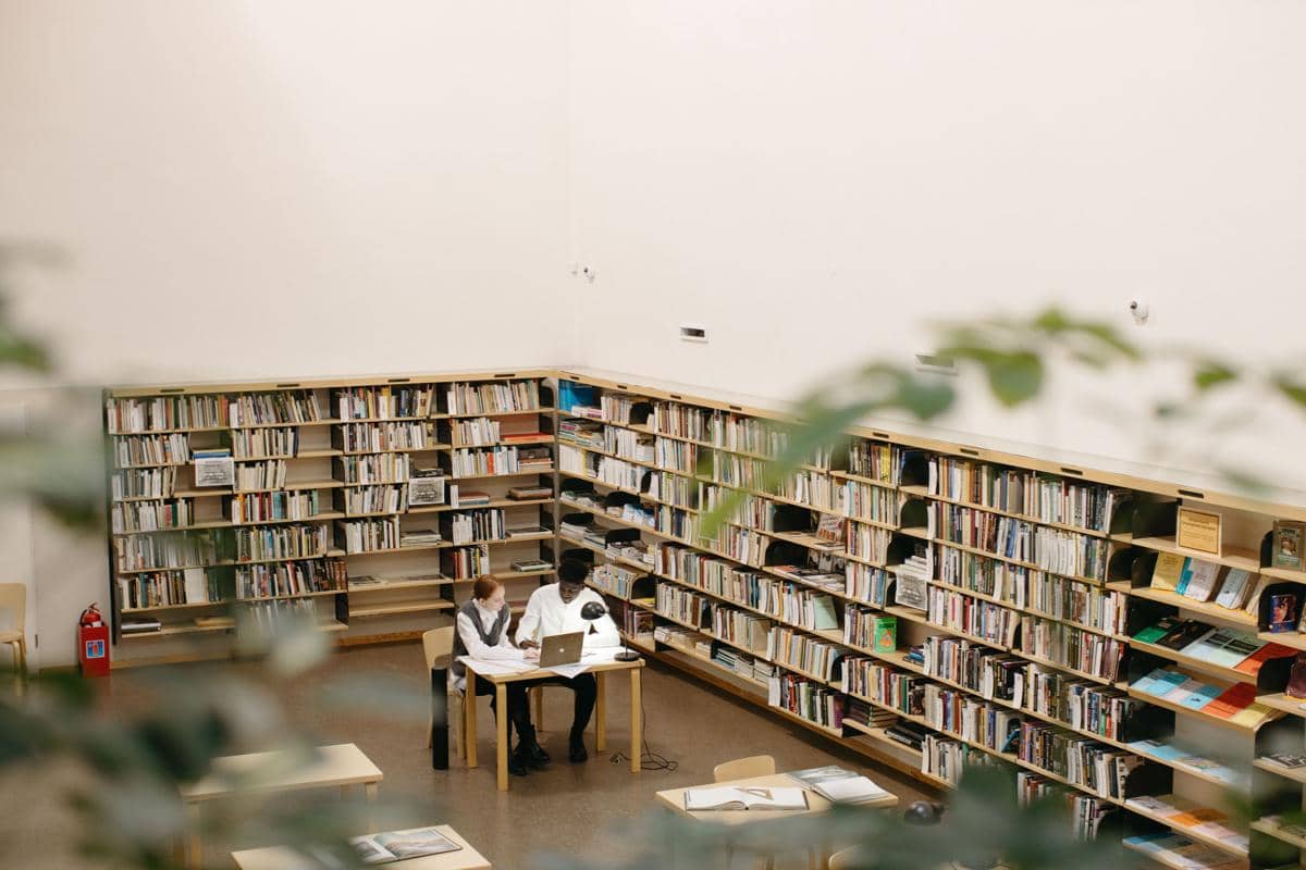 Ilustrasi mahasiswa belajar bersama menggunakan laptop di perpustakaan