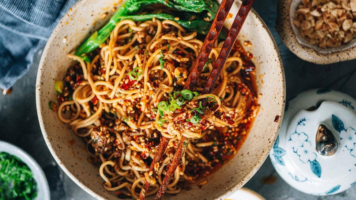 Semangkuk dan dan mian, mi khas Sichuan dengan saus pedas, daging cincang, dan taburan daun bawang segar.
