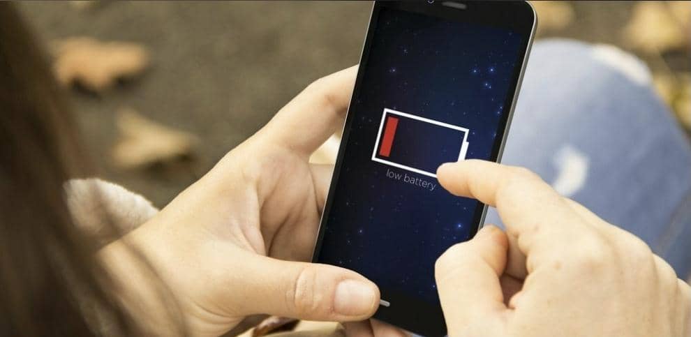 Foto seorang pria yang frustrasi memegang smartphone Android dengan layar menunjukkan ikon baterai berwarna merah di 1 persen.
