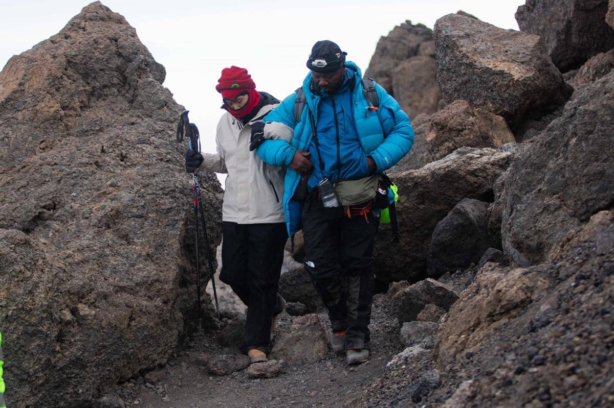 ilustrasi dua orang pendaki sedang melakukan perjalanan turun dari gunung