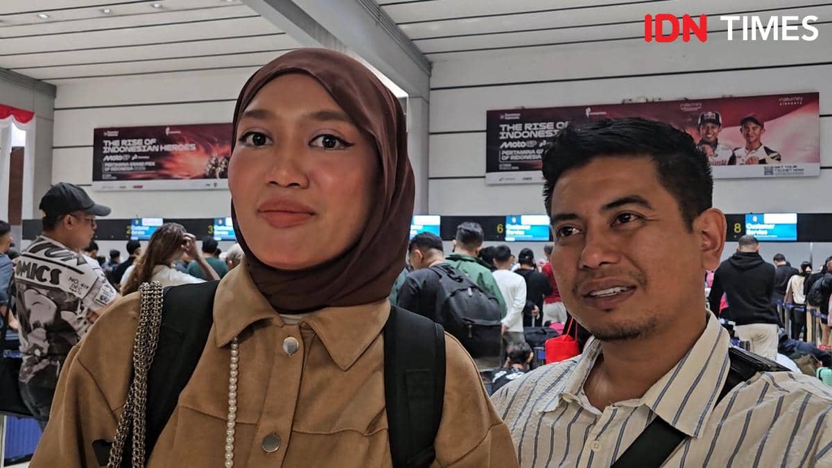 Seorang penumpang asal Malaysia duduk menunggu di area Bandara Soekarno-Hatta sambil membawa barang bawaan.