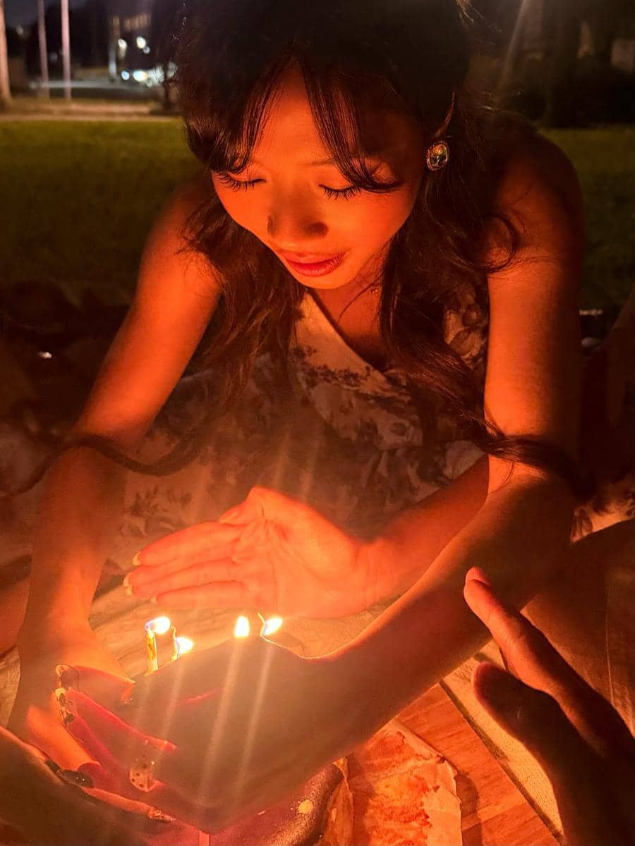 Potret Christy Gardena saat merayakan ulang tahun, mengenakan busana putih dan berpose di depan dekorasi.
