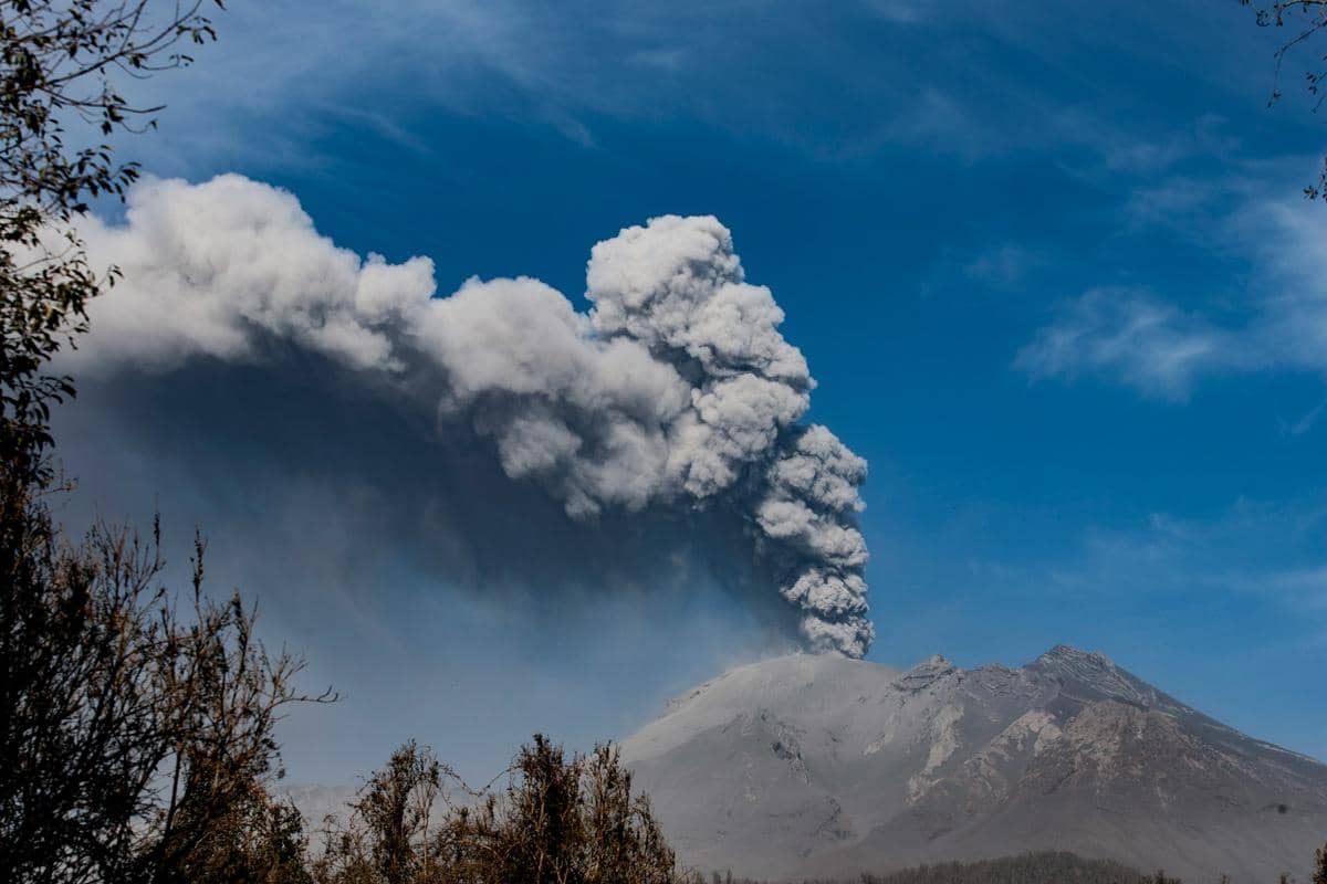 Kabut asap vulkanik atau vog menyelimuti lereng gunung berapi, membatasi jarak pandang di bawah langit kelabu.