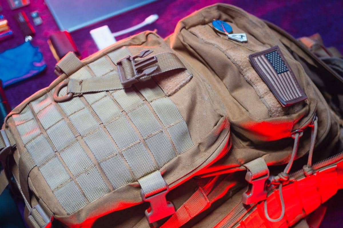 Ilustrasi tactical backpack dengan desain fungsional, sejumlah kompartemen, serta tali untuk membawa perlengkapan.