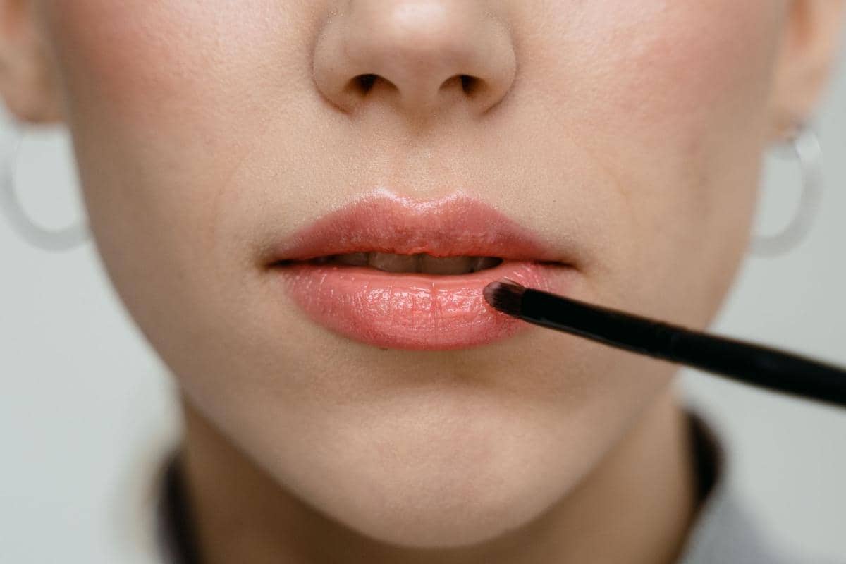 memakai riasan bibir dengan kuas