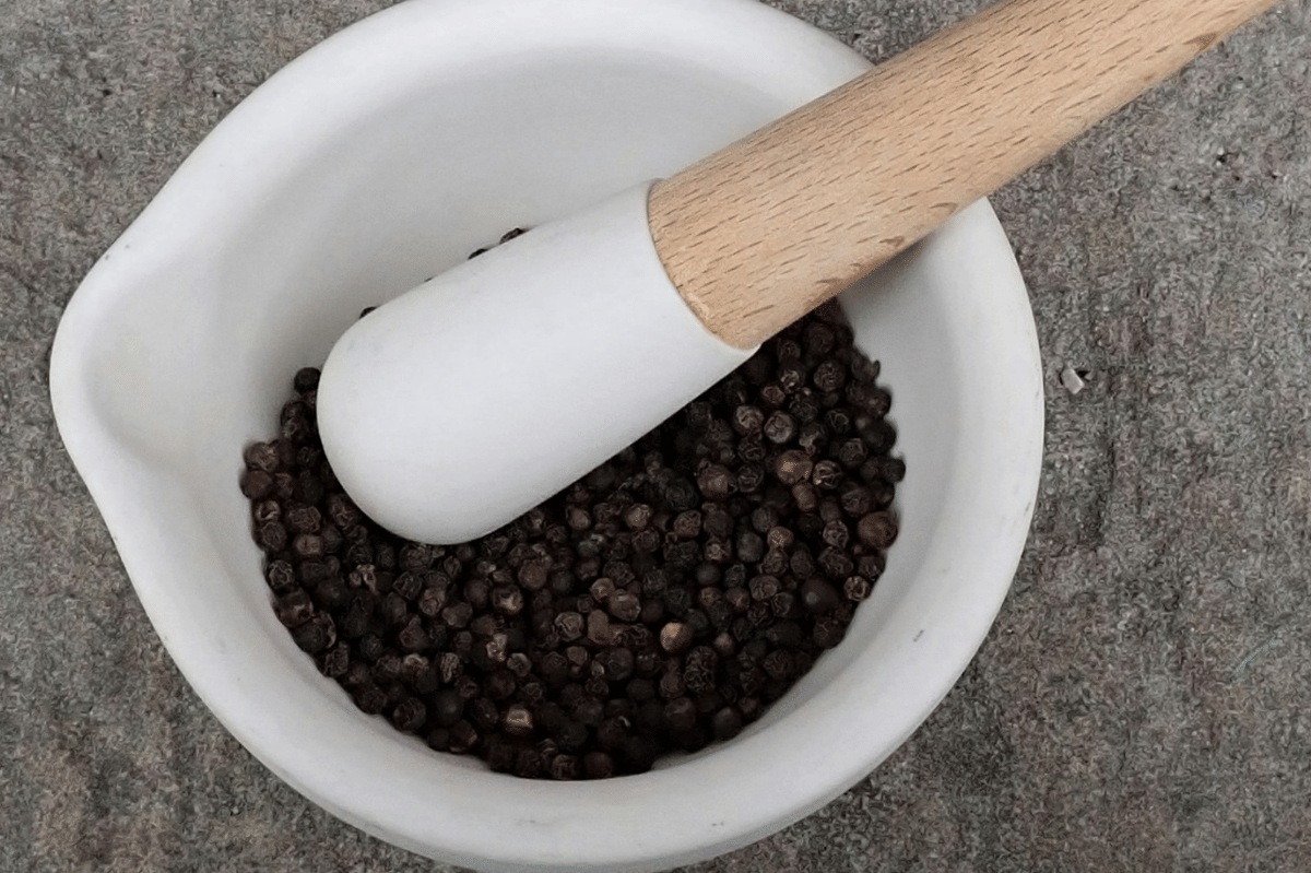 Ilustrasi butiran lada hitam berwarna gelap sebagai bumbu dapur yang umum digunakan untuk masakan.