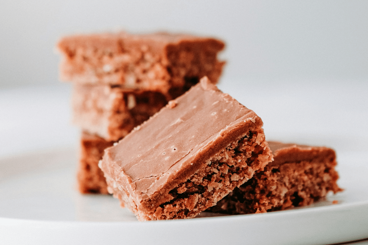 Potongan strawberry chocolate lemon bar berlapis cokelat dan lemon, dihiasi irisan stroberi segar di atas piring.