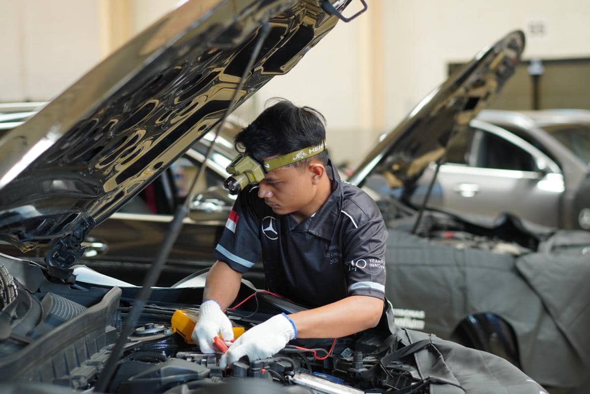 Para mekanik Mercedes-Benz mengikuti kompetisi dengan berbagai simulasi pengujian di area kerja.