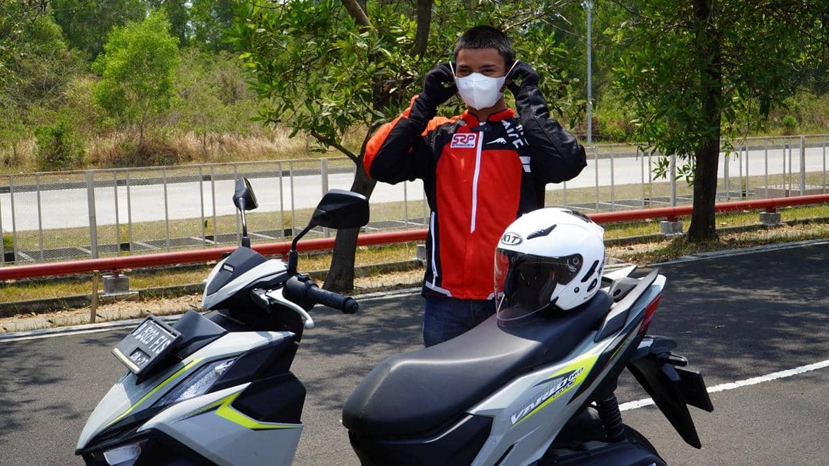 Seorang pengendara sepeda motor mengenakan masker saat berkendara, sesuai anjuran wajib pakai masker.