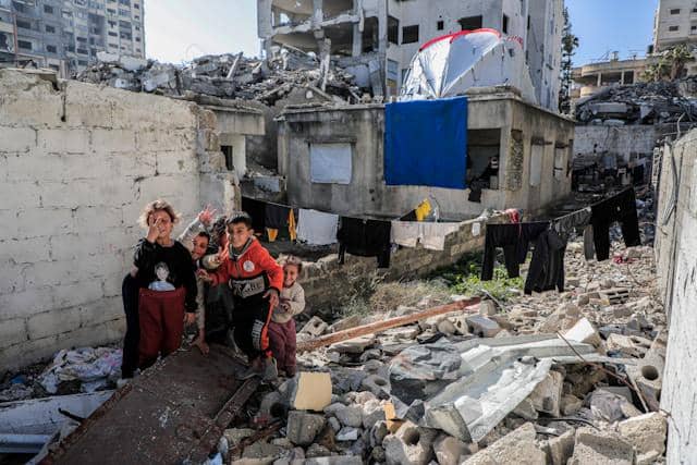 Anak-anak Gaza tersenyum di tengah reruntuhan bangunan hancur.