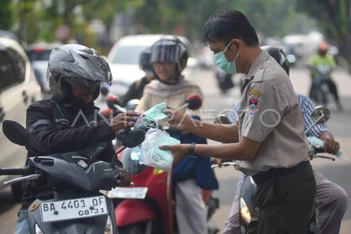 Seorang petugas menyerahkan masker kepada pengendara sepeda motor di Padang, Sumatera Barat, pada Senin, 7 September 2026.