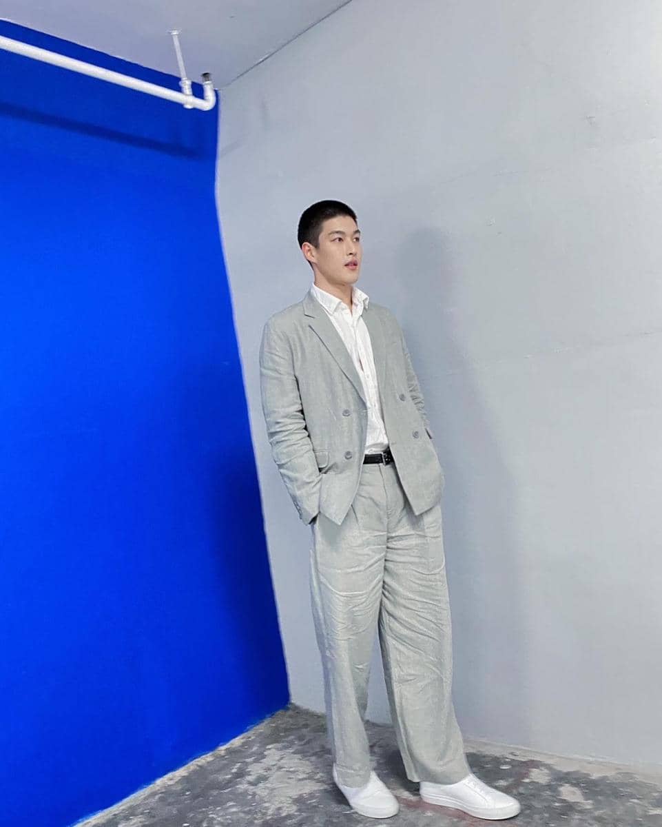 Krating Khunnarong tampil dalam OOTD setelan jas bergaya rapi dan elegan, dipadukan dengan kemeja putih.