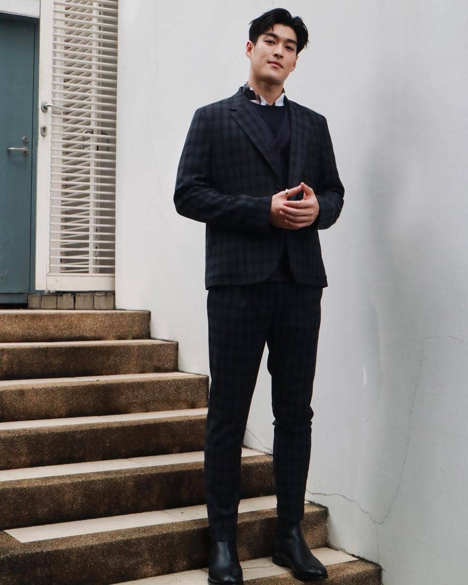 Krating Khunnarong berpose mengenakan setelan jas sebagai inspirasi OOTD bergaya rapi dan formal.