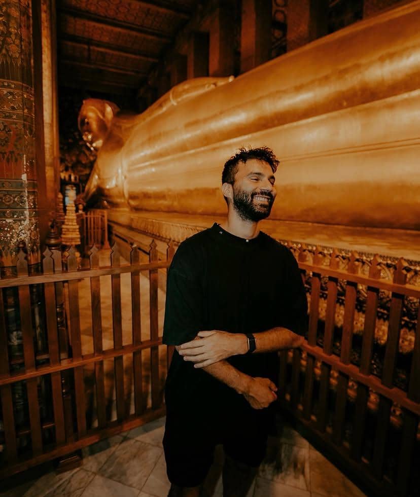 Potret R3HAB, DJ dan produser musik, mengenakan kaus hitam sambil memandang kamera dengan latar dinding bernuansa gelap.