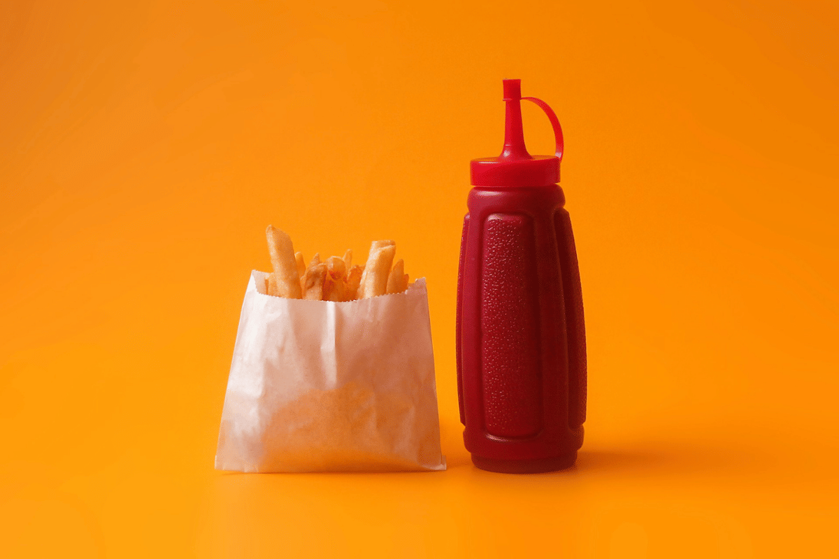 Ilustrasi saus spicy ketchup berwarna merah dalam mangkuk kecil, disajikan sebagai pelengkap makanan.