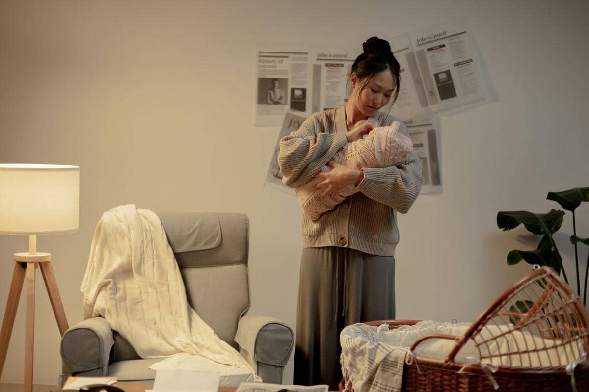 Ilustrasi seorang ibu menggendong bayi kecil dalam pelukannya, menggambarkan kedekatan dan kasih sayang.