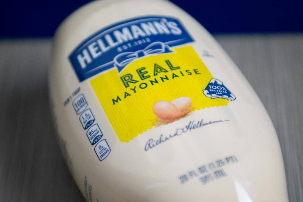 Ilustrasi mayones sebagai saus pelengkap untuk berbagai hidangan, disajikan dalam wadah di atas permukaan meja.