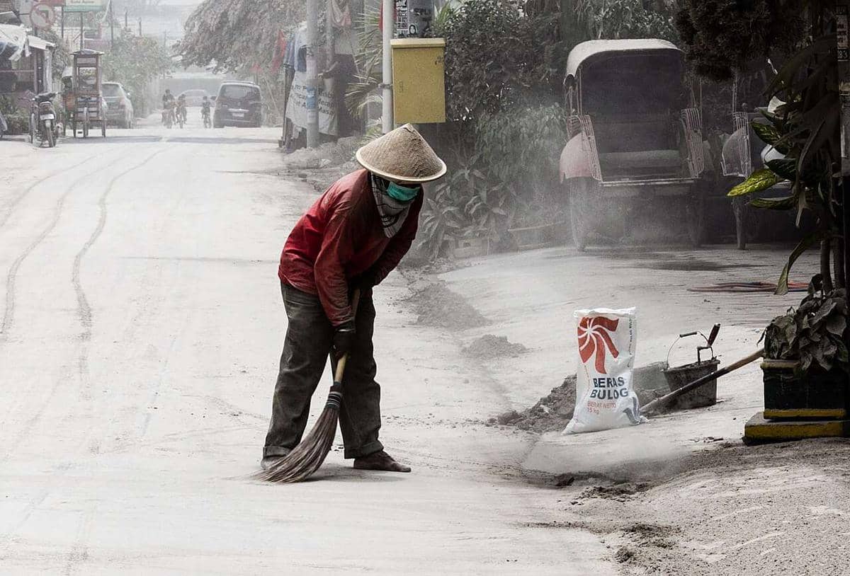 Seorang warga sedang menyapu abu di jalan akibat letusan Gunung Kelud pada tahun 2014.