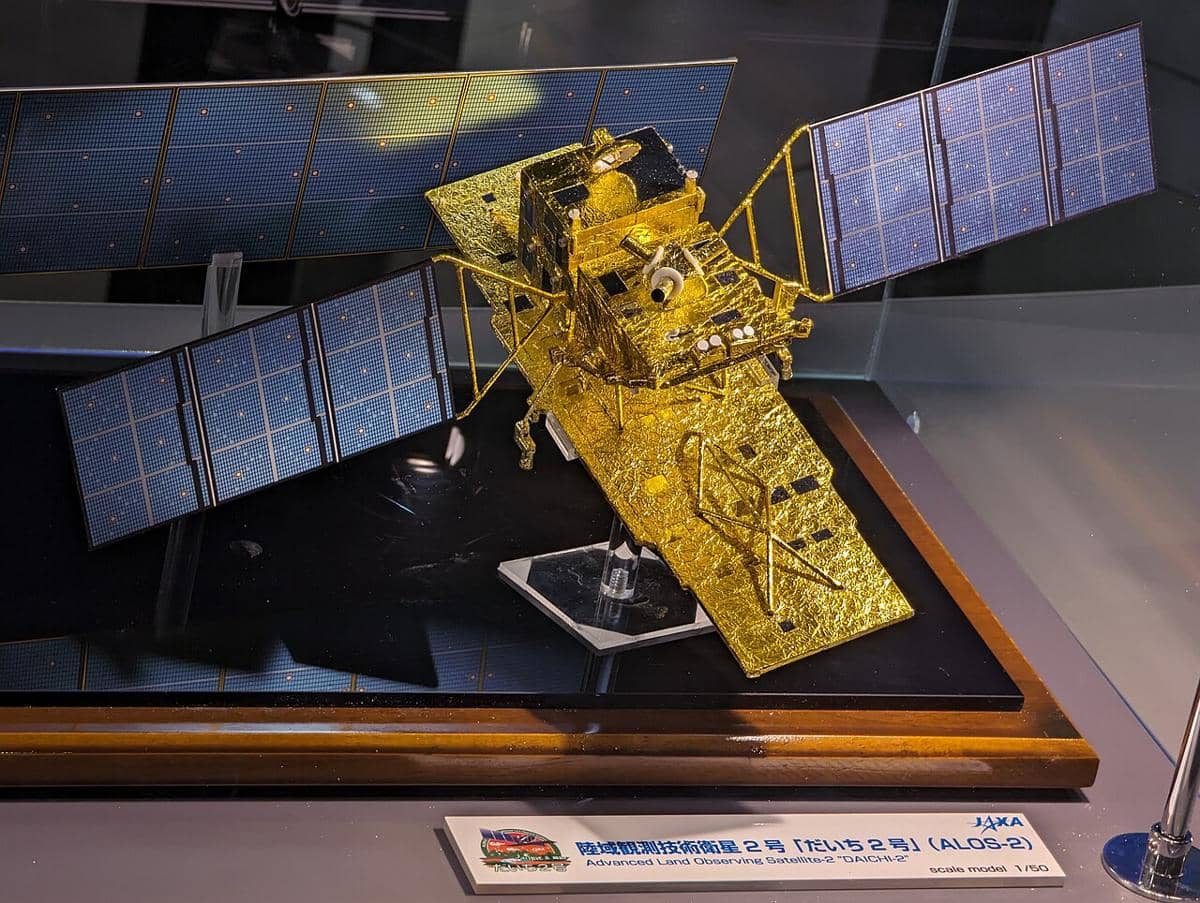 Ilustrasi satelit ALOS-2 mengorbit di atas Bumi dengan panel surya terbentang di tengah latar ruang angkasa.