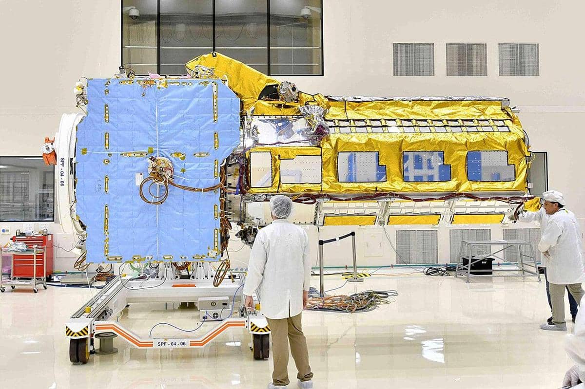 Ilustrasi satelit NISAR hasil kolaborasi NASA dan ISRO dengan antena radar besar serta panel surya di latar angkasa.