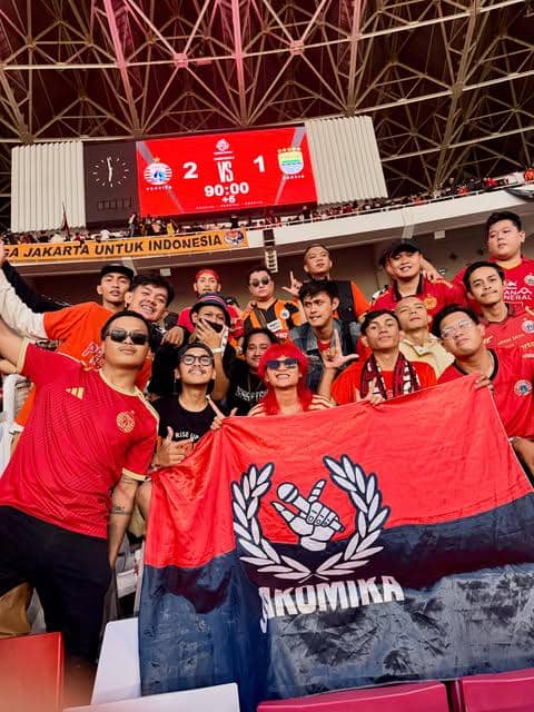 Seorang perempuan tersenyum sambil berpose di tribun Stadion GBK saat menyaksikan laga Persija melawan Persib.